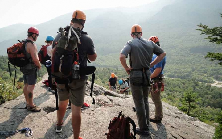 a group of gap year students listen to an instructor give a rock climbing lesson on an outward bound expedition 